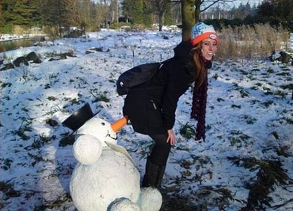 A woman posing next to a snowman in the snow, looking affectionately
Keywords Used: Snowman, Snow