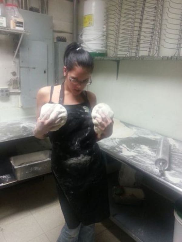 A woman in an apron is holding dough in her hands, showcasing her baking skills and expertise.