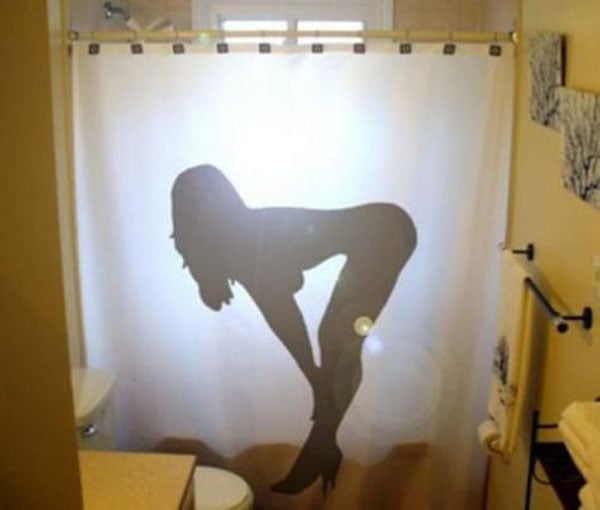 A bathroom with a shower curtain featuring a woman silhouette that screams