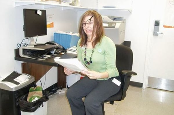 A woman sitting in a chair reading a paper titled