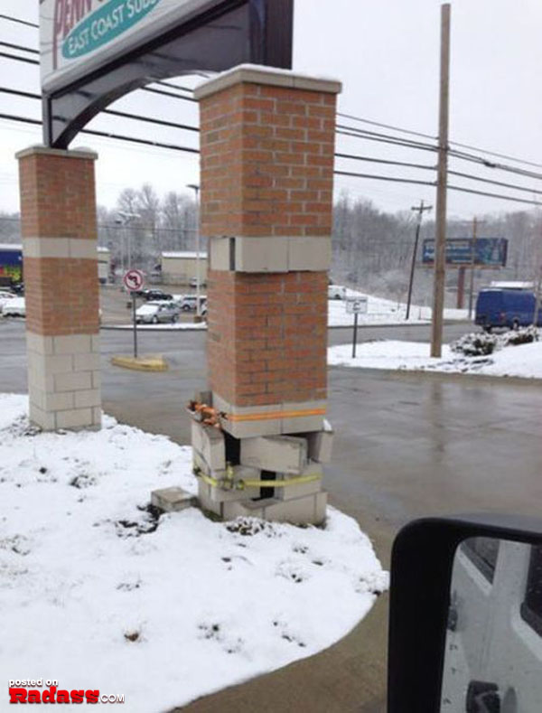 A brick wall standing proudly in the middle of a snowy parking lot, defying the cold and providing shelter.