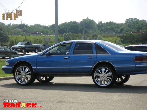 A blue chevrolet impala parked in a parking lot, wondering if it will be noticed.