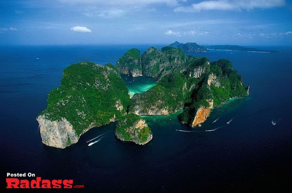A boat in the water near a rock island in the ocean.