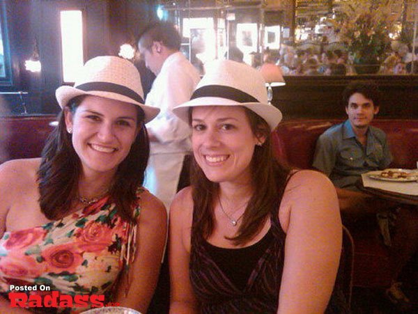 A woman photobombs a celebrity while wearing a stylish hat.
