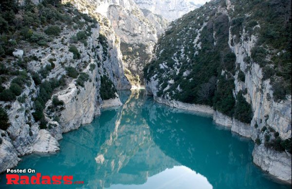 A serene blue river flows through a remote canyon, allowing a peaceful escape from civilization.