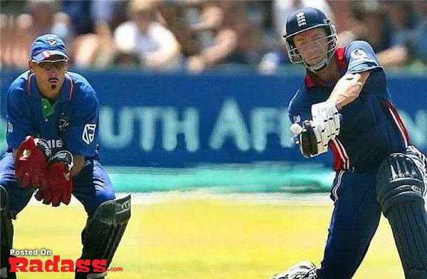 An England cricket player swinging his bat at a ball during a match.