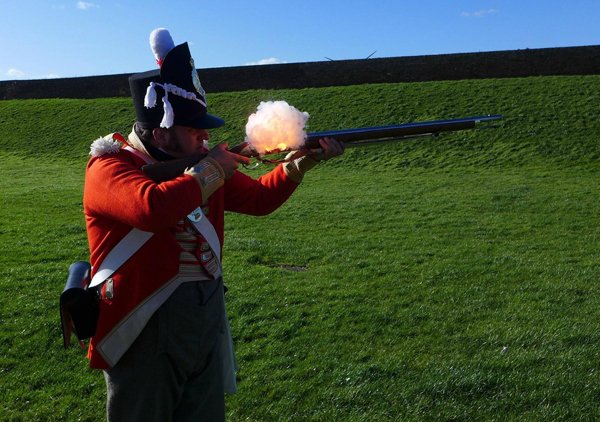 A man in a red uniform firing a rifle, providing plenty of cool pics to brighten your Saturday.