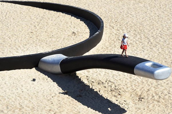 A person on a large metal object in the sand, providing plenty of cool pics to brighten your Saturday.