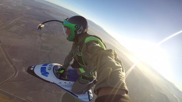 A man with cool pics flying a jet ski in the sky.
