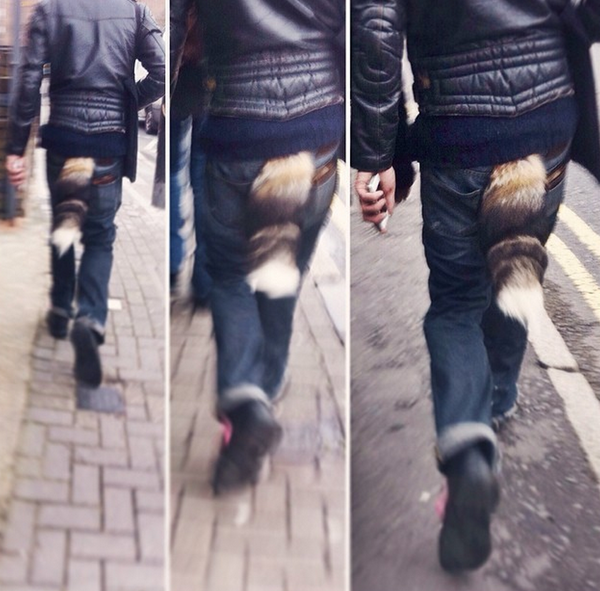 A hipster man wearing a furry tail.