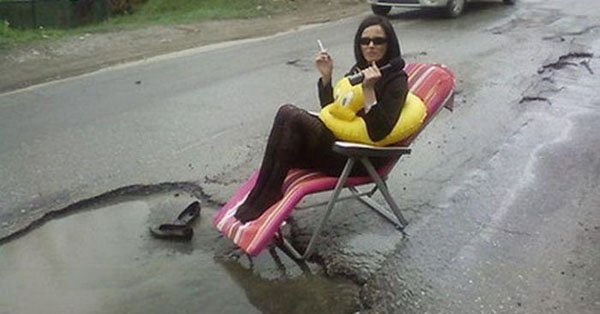 A woman sitting on a chair in a pothole.