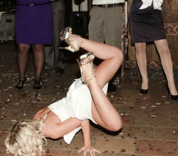 A woman is doing a flip on the floor at a party.