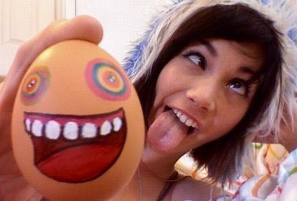 A girl holding an egg with a face painted on it.