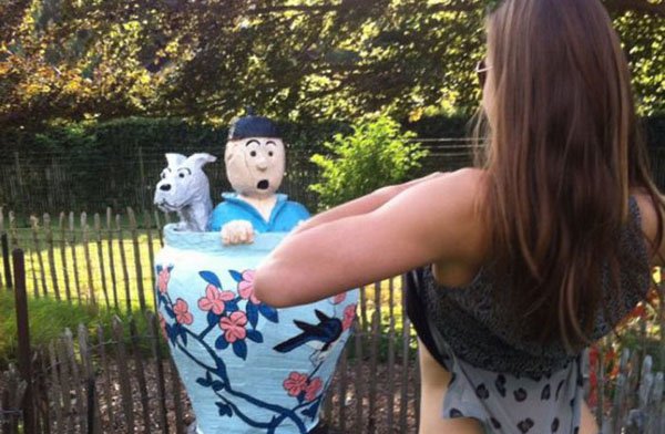 A woman standing next to a statue of a woman and a dog.