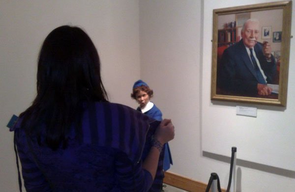 A woman is looking at a painting of a man.