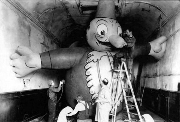 A group of people painting a giant pinocchio for the Macy's Day Parade.