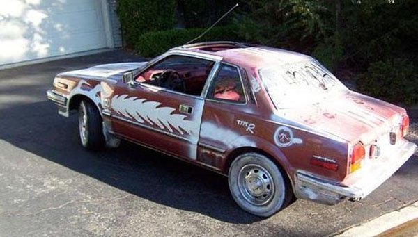 A bizarrely colored car parked in a driveway.