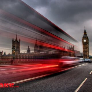 A double decker bus driving down a street in London, captured in beautiful architecture photographs.