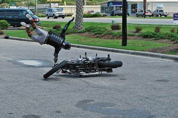 A person doing a flip on a motorcycle in the street, face plants.