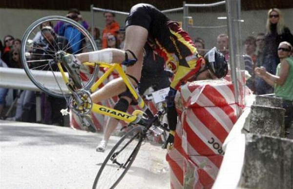 A man on a bike is leaning over a barrier, face planting.