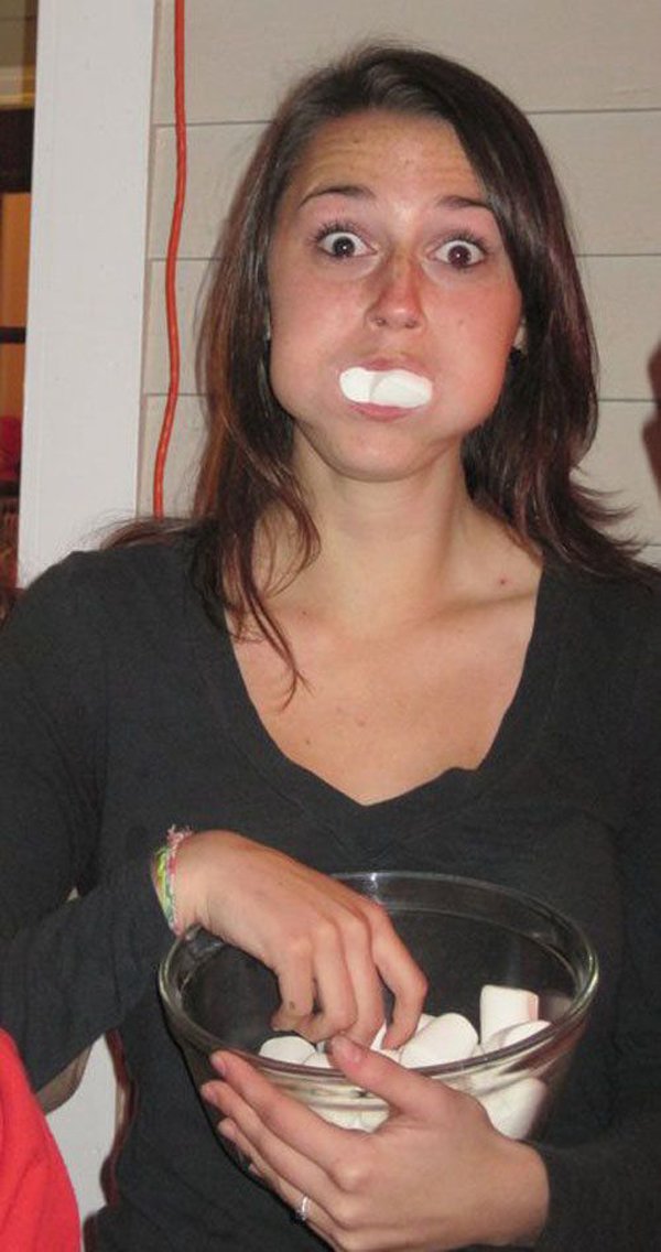 A woman holding a bowl of marshmallows and contemplating,