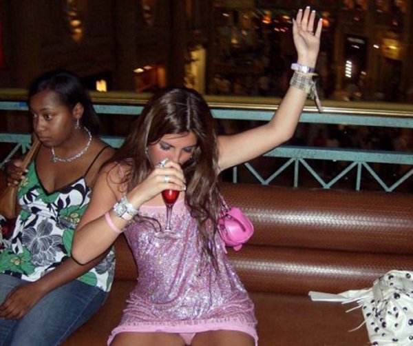 A woman in a pink dress sitting on a couch, giving a playful expression as if to say