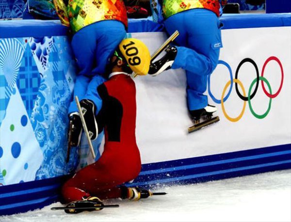 Two olympic skiers gracefully navigate a slalom course with smiles on their faces.