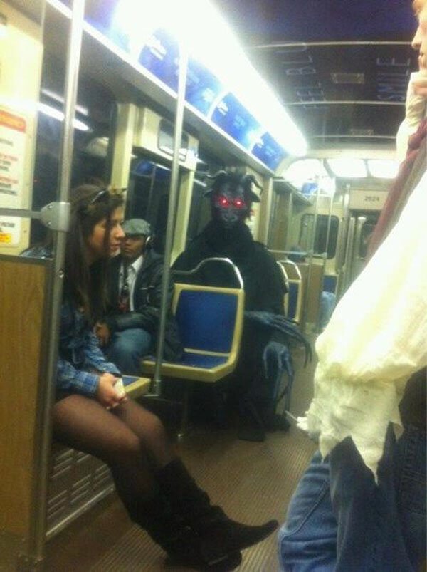 A group of people sitting on a subway with a mysterious man in a mask, fueling intrigue and curiosity.