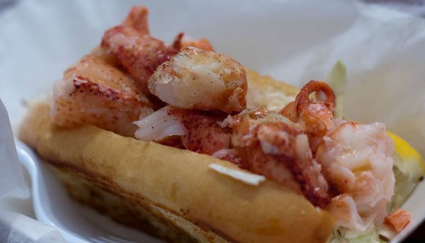 A food porn-worthy lobster hot dog is perched on a paper plate.