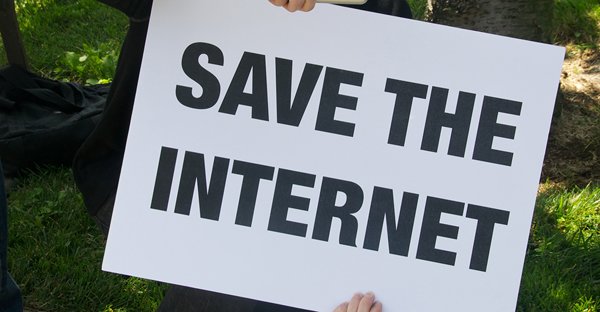 A person holding up a sign that says save the internet, bare.