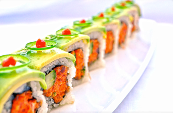 An avocado and carrot-topped sushi roll that is pure food porn.
