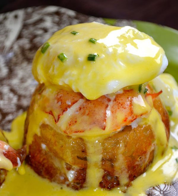 A plate topped with brunch delicacy eggs benedict and creamy hollandaise sauce.