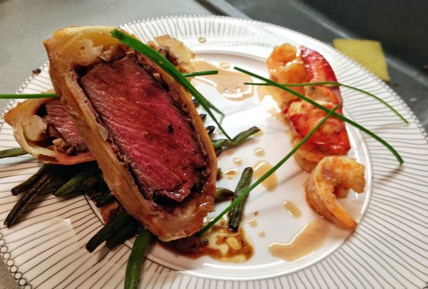A mouthwatering plate featuring a succulent steak, savory shrimp, and crisp green beans.