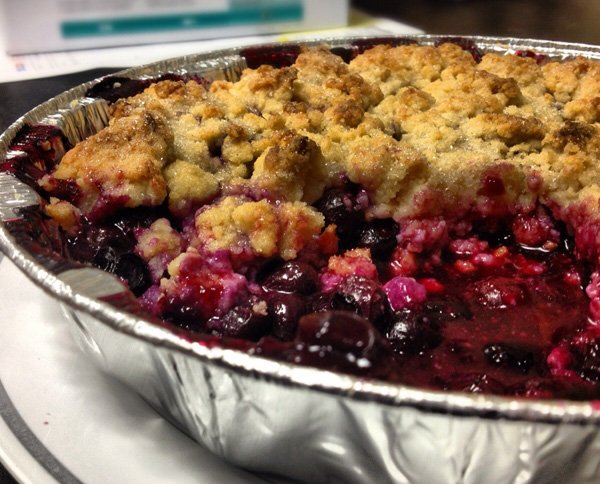 A mouthwatering blueberry crumble in a pan, tantalizingly displayed on a table that will make you crave more.