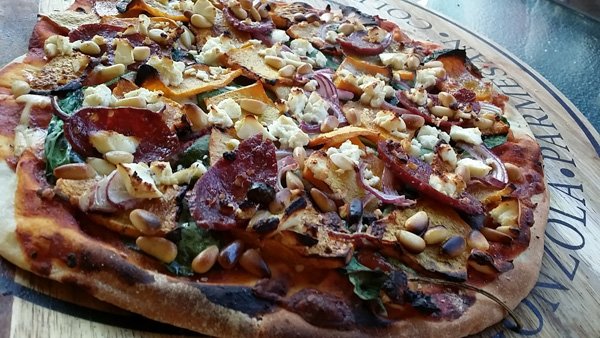 A mouthwatering pizza presentation on a wooden board perfect for food porn enthusiasts.