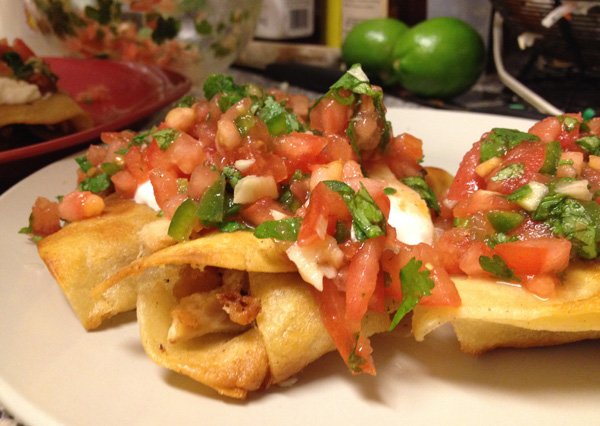 A plate of mouthwatering enchiladas topped with salsa and sour cream that will make you crave for more.