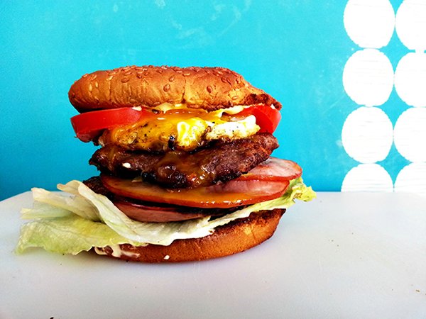 A mouthwatering burger on a cutting board, perfect for satisfying your hunger cravings with a hint of food porn.