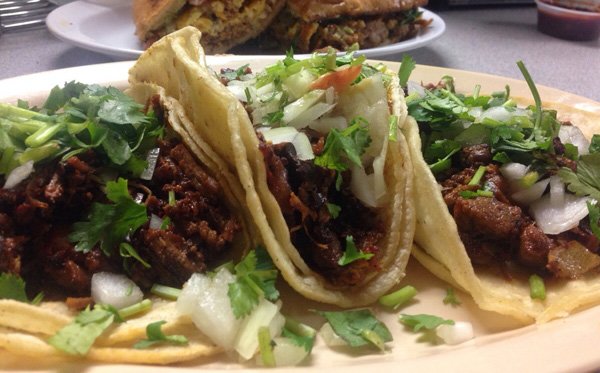 Food porn: Three tacos are sitting on a plate.