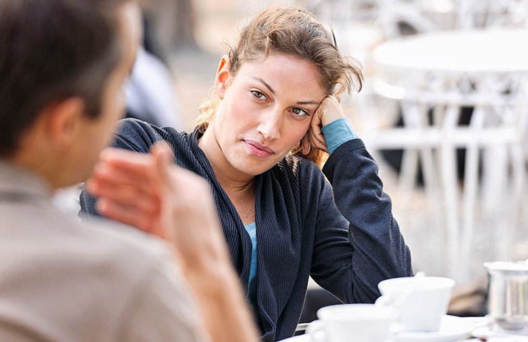 A couple discussing their deal-breakers at an outdoor cafe.