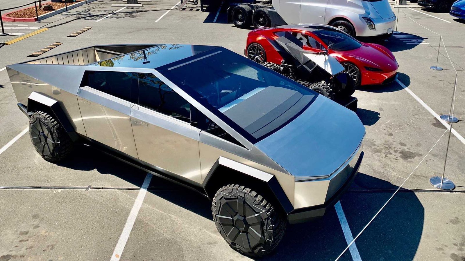 Two silver vehicles parked in a parking lot, Cybertruck coming.