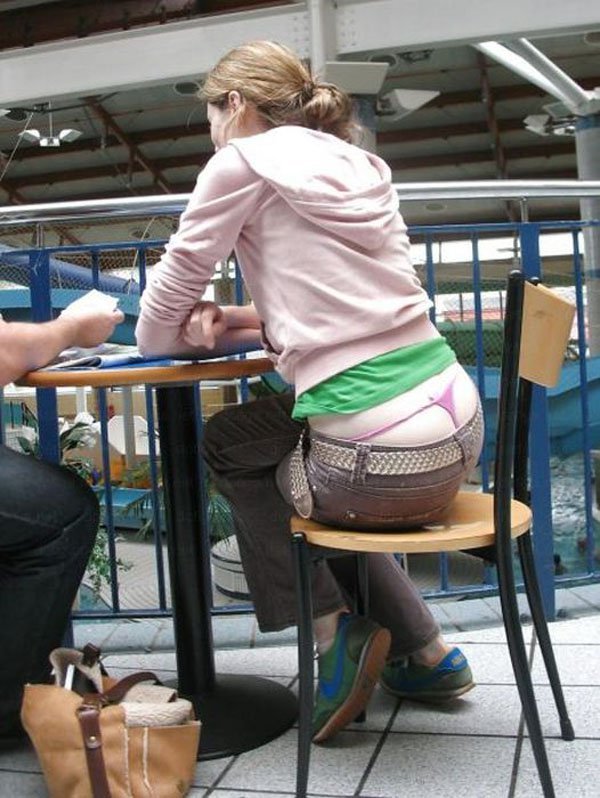 A woman sitting at a table, with a whale tail tattoo visible.