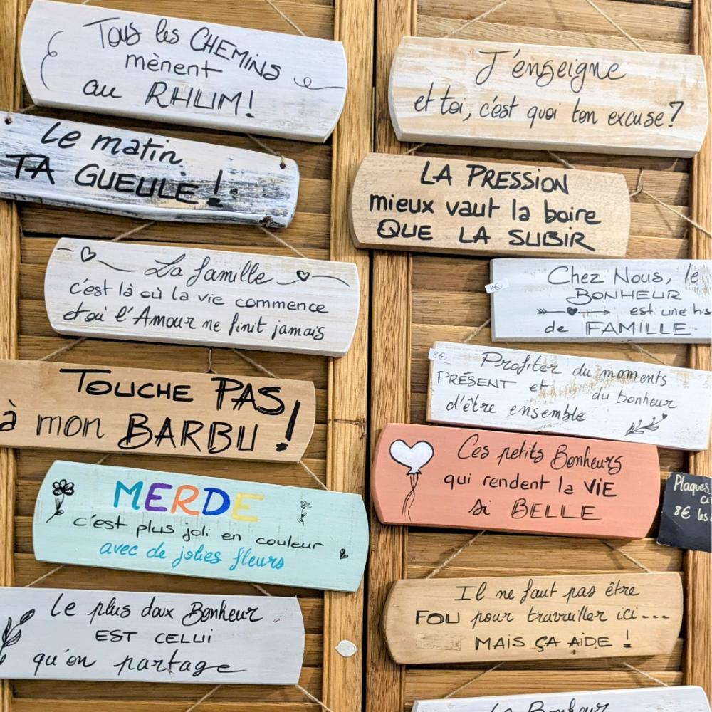 Plaques humoristiques et citations inspirantes sur un mur.