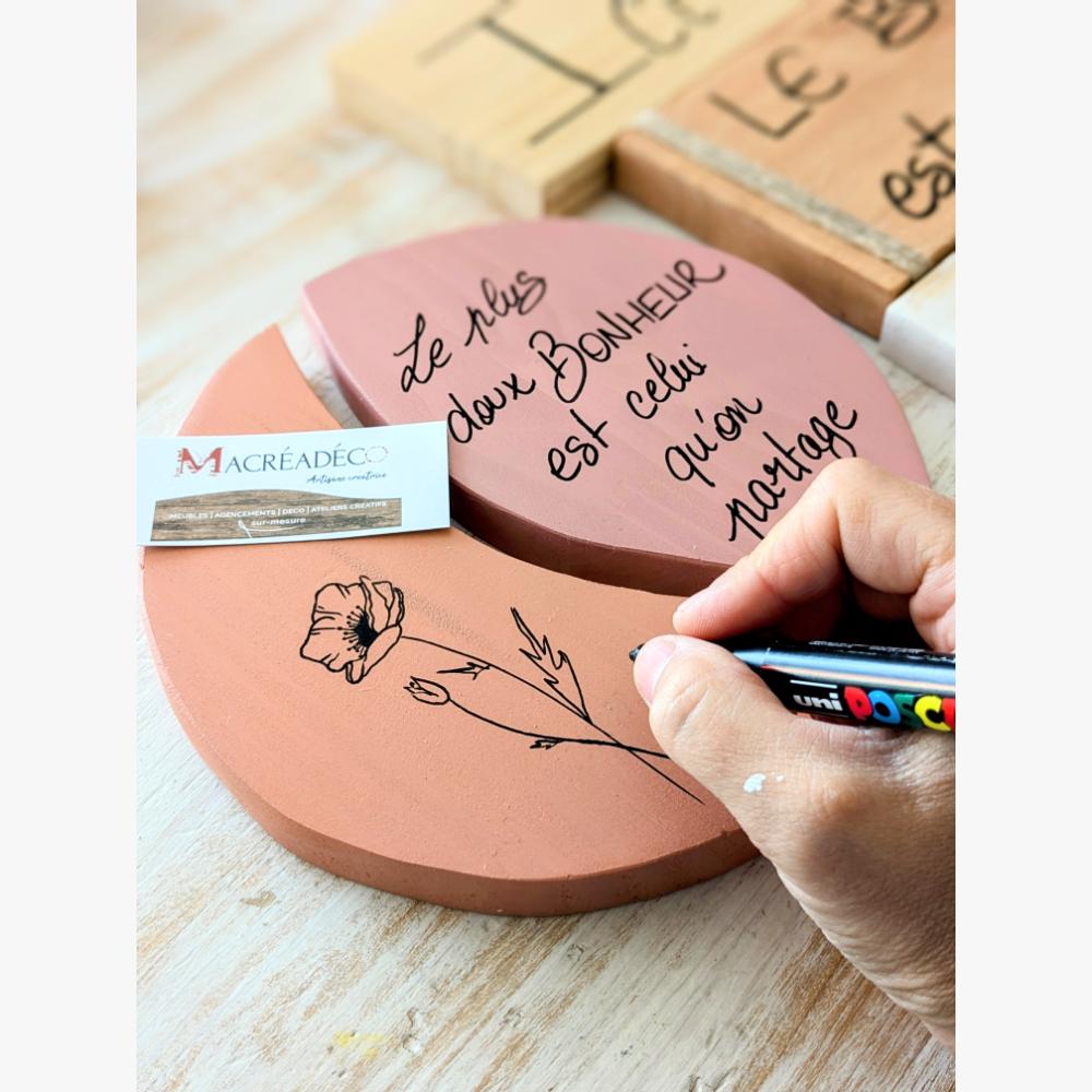 Plaque bois avec citation et fleur dessinée.