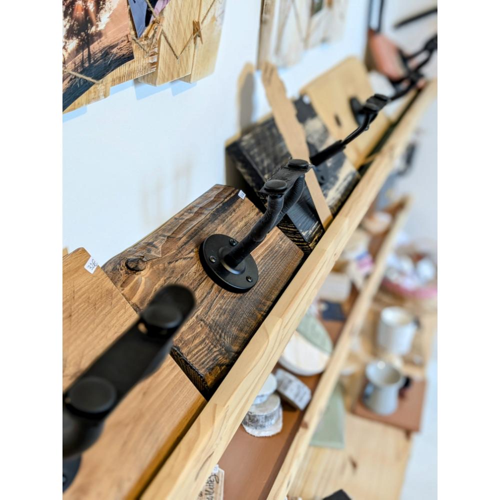 support-guitare-mural-insutriel-cadeau-bois-personnalisé-artisanal Étagère en bois avec crochets métalliques noirs.