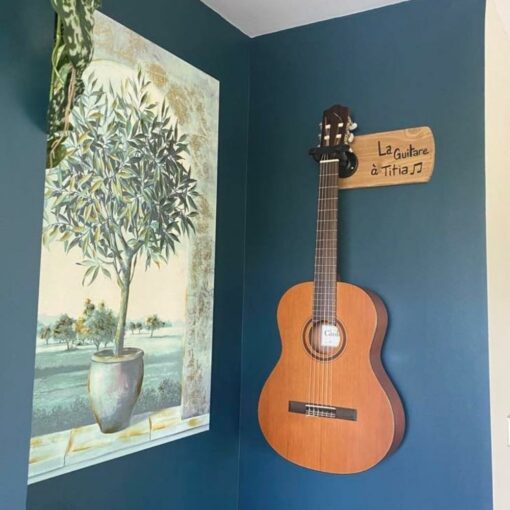Guitare classique accrochée au mur bleu.
