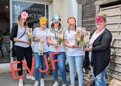 Cinq femmes tenant des plantes EVJF devant magasin.