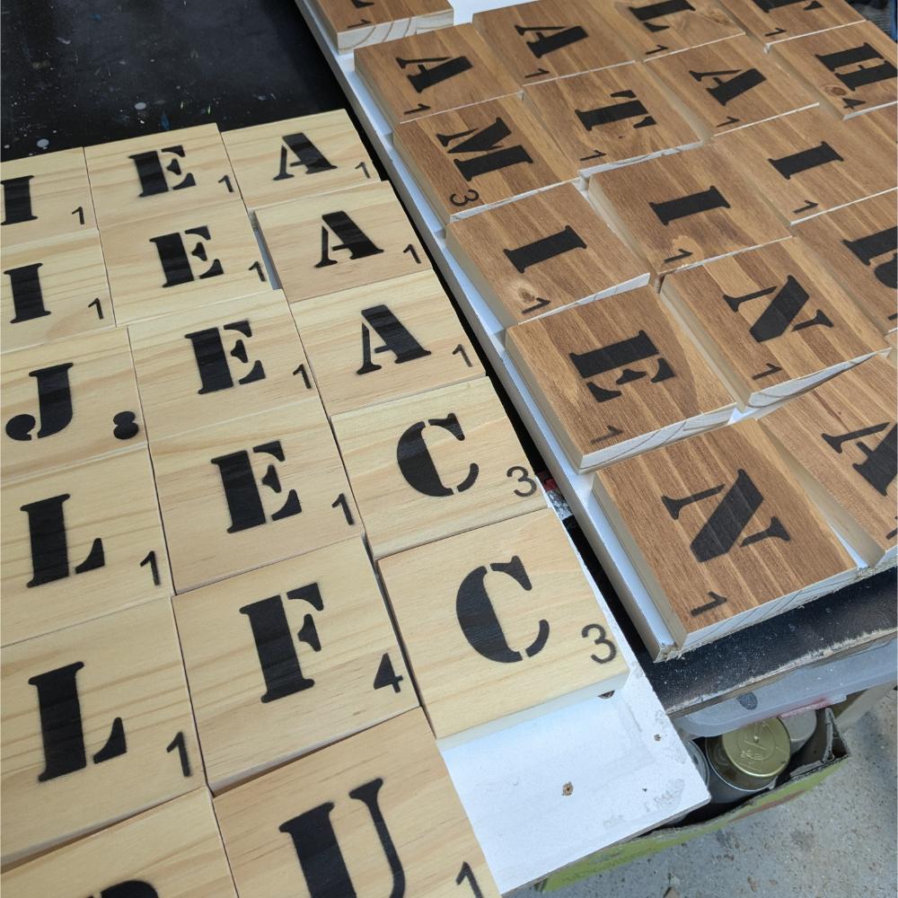 scrabble-mural-bois-lettre-géant-mots-prenom-personnalisé-artisanal Tuiles de Scrabble en bois avec lettres noires.