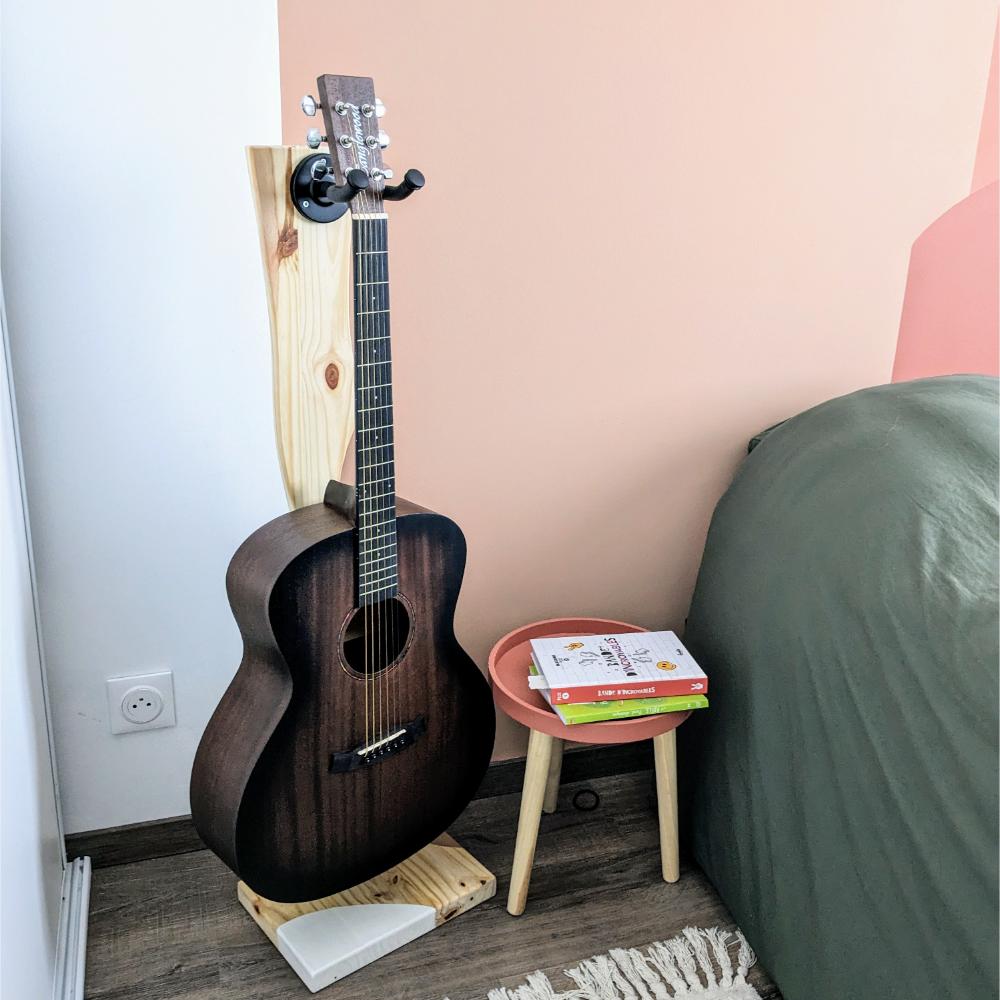 support-guitare-à-poser-pied-cadeau-bois-personnalisé-artisanal Guitare acoustique sur pied à côté d'une table.