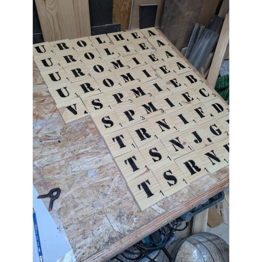 scrabble-mural-bois-lettre-géant-mots-prenom-personnalisé-artisanal Lettres de scrabble géantes sur une table en bois.