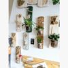 suspension-végétale-déco-murale-bois-citation-personnalisé-artisanal Mur décoratif avec plantes et vases suspendus.